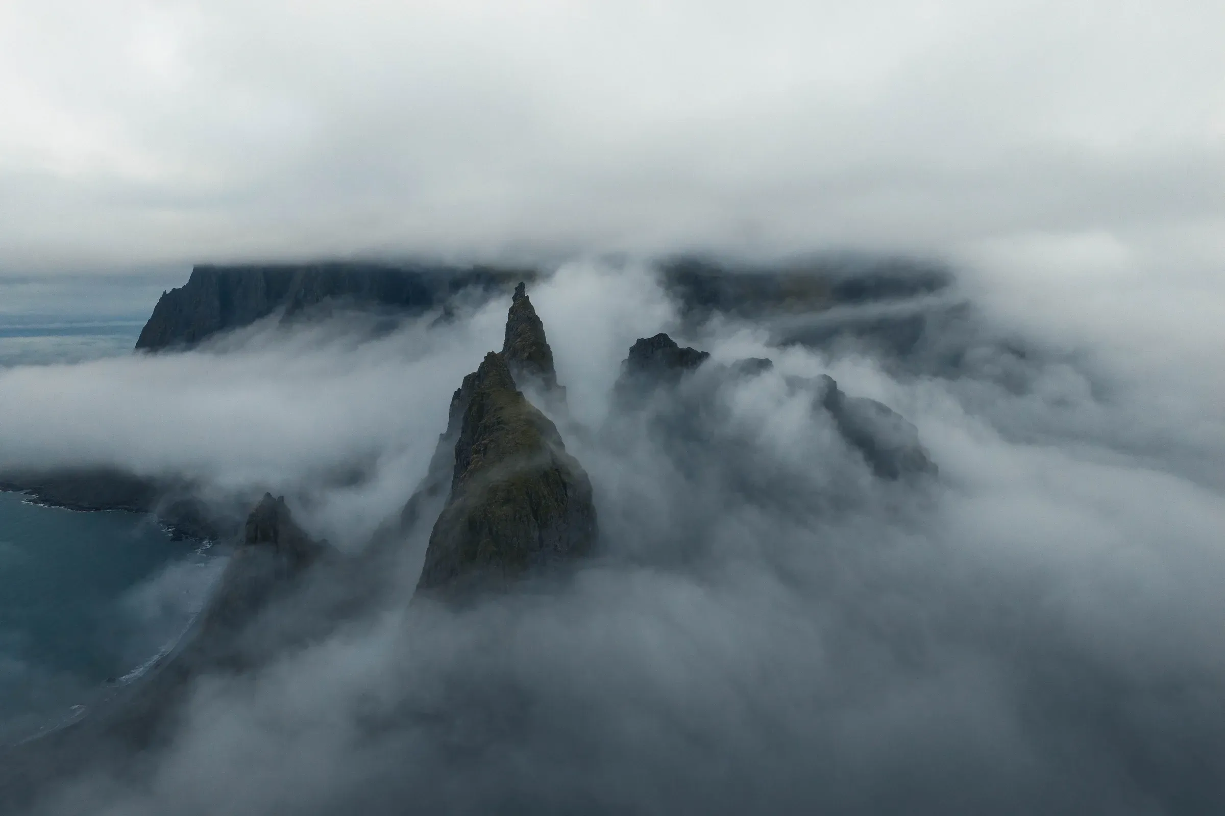 Dark mountain peaks emerging through low cloud