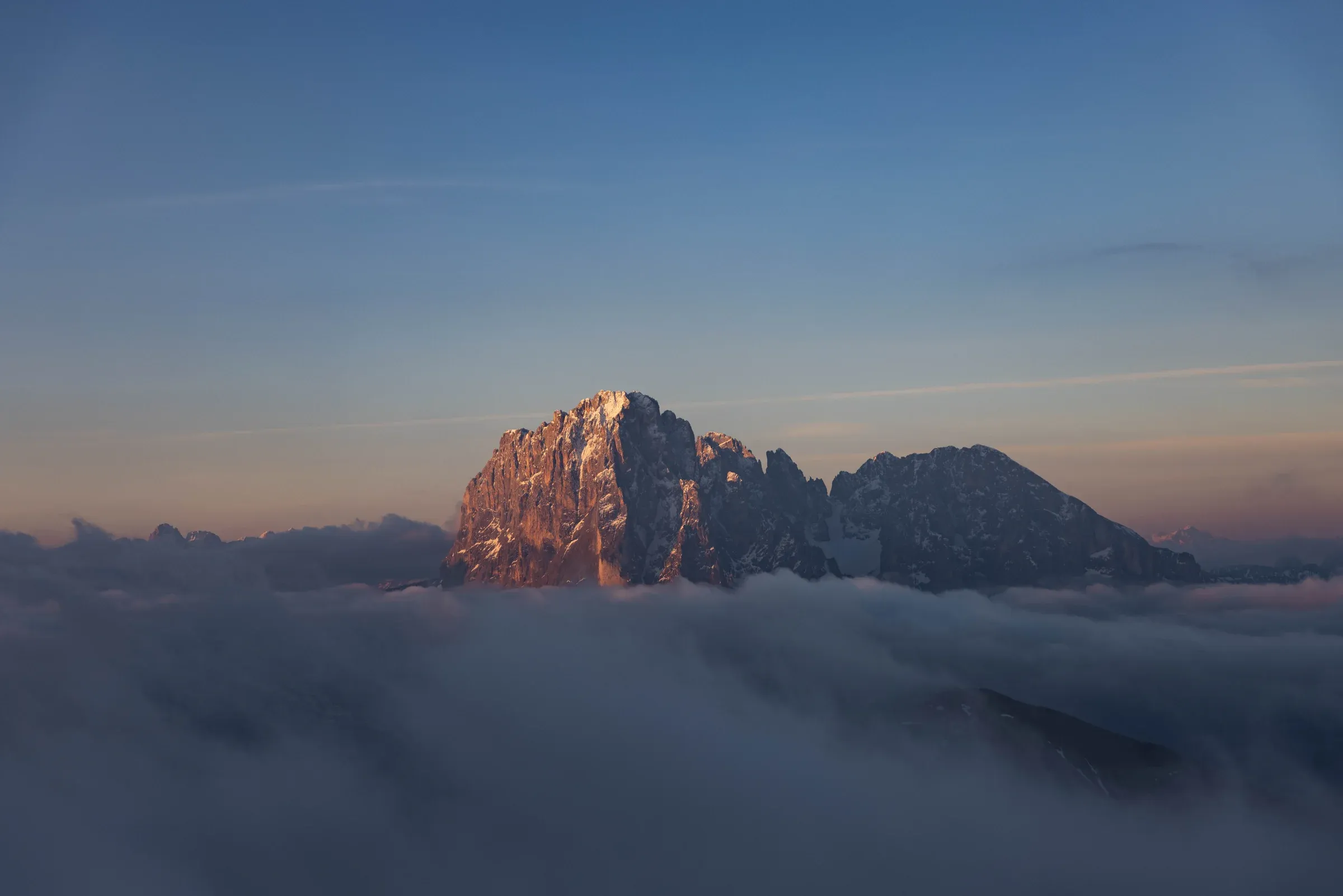 Warm light on a rocky summit floating above a sea of cloud
