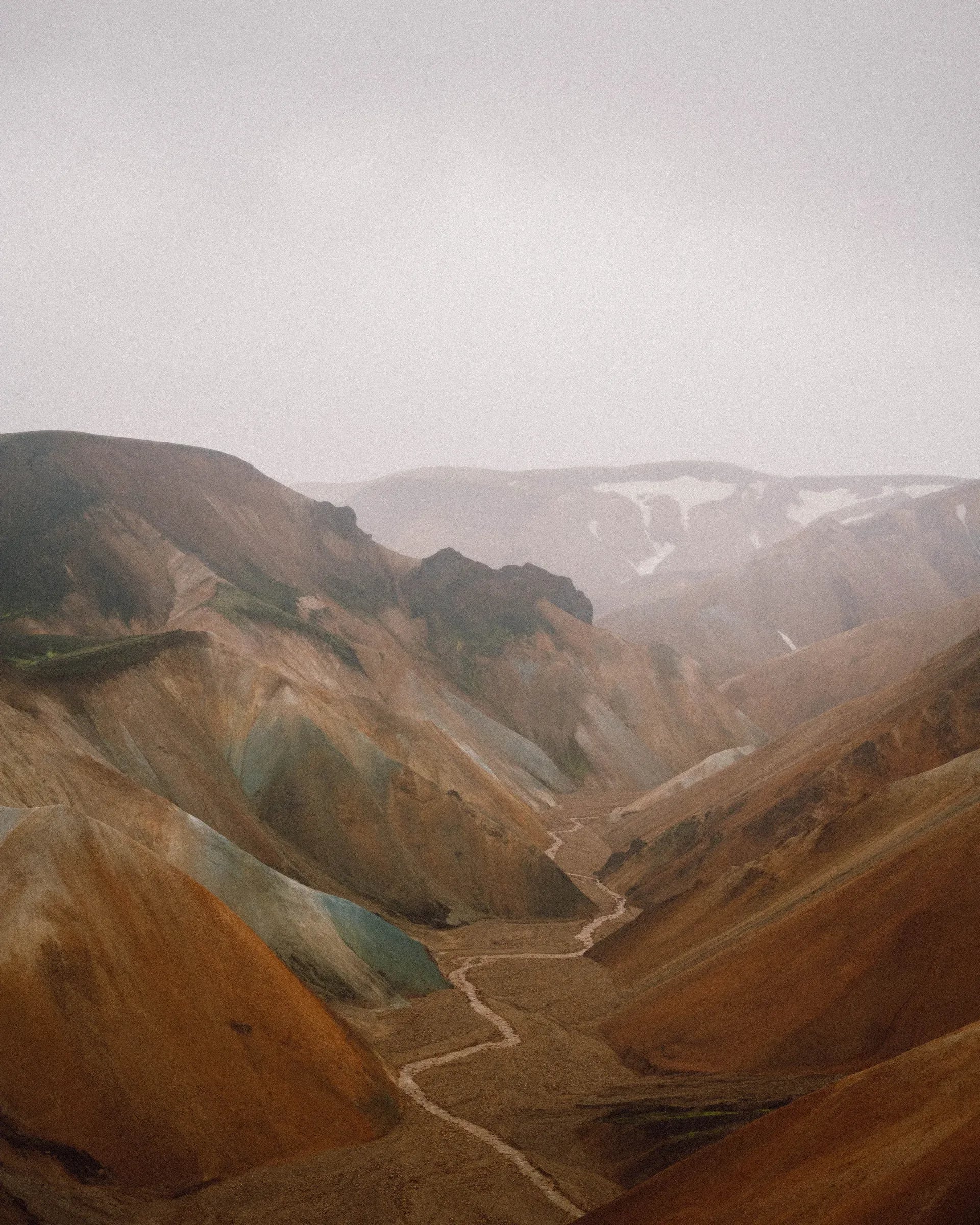An ochre valley and winding stream disappearing into mist